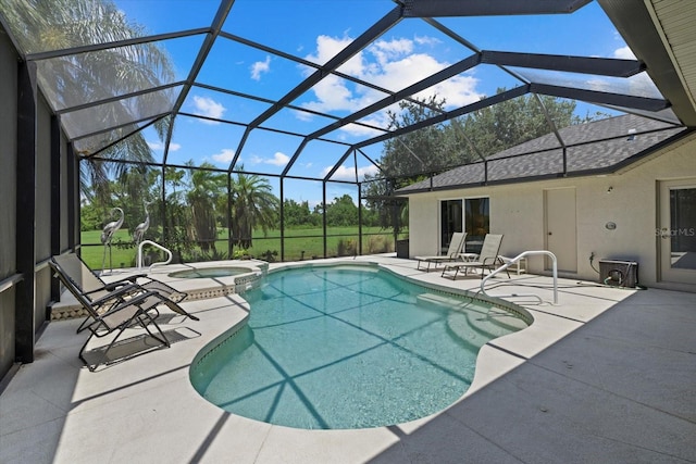 view of swimming pool with a patio, a pool with connected hot tub, and glass enclosure