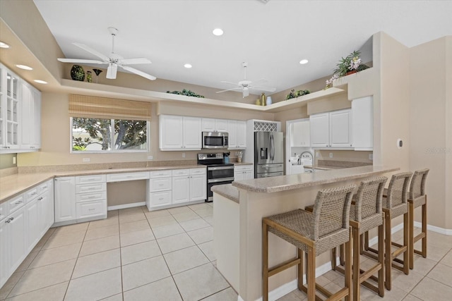kitchen featuring stainless steel appliances, a peninsula, a ceiling fan, and light tile patterned floors