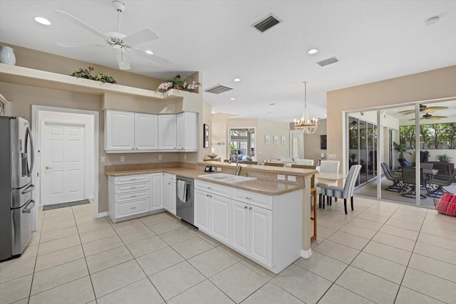kitchen with ceiling fan with notable chandelier, a peninsula, visible vents, a sink, and stainless steel appliances