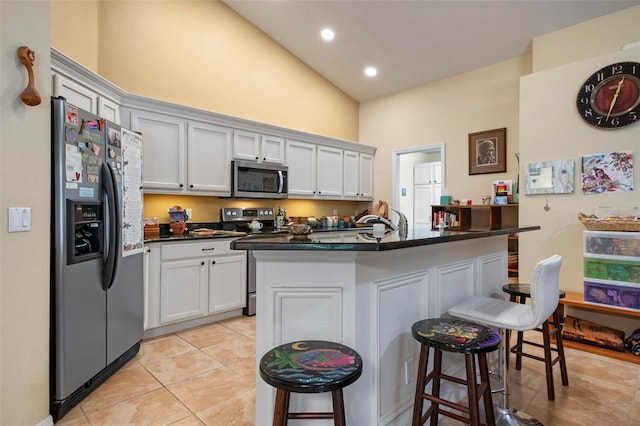 kitchen featuring stainless steel appliances, light tile patterned floors, white cabinets, and a kitchen breakfast bar