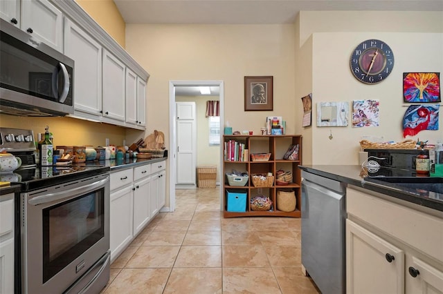 kitchen with stainless steel appliances, white cabinetry, and light tile patterned floors