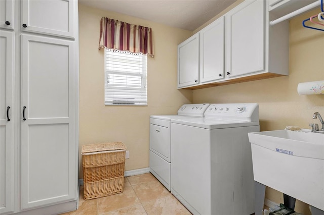 washroom featuring sink, light tile patterned floors, washing machine and dryer, and cabinets