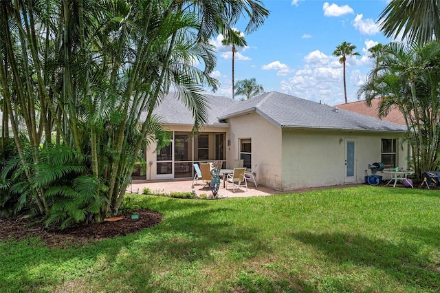 rear view of house with a yard, a sunroom, and a patio