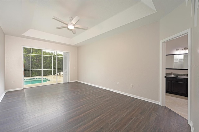 spare room featuring dark hardwood / wood-style floors, ceiling fan, a raised ceiling, and sink