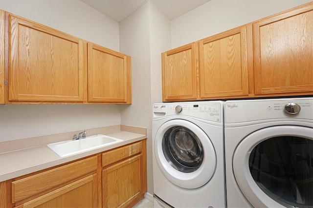 clothes washing area featuring washing machine and dryer, sink, and cabinets