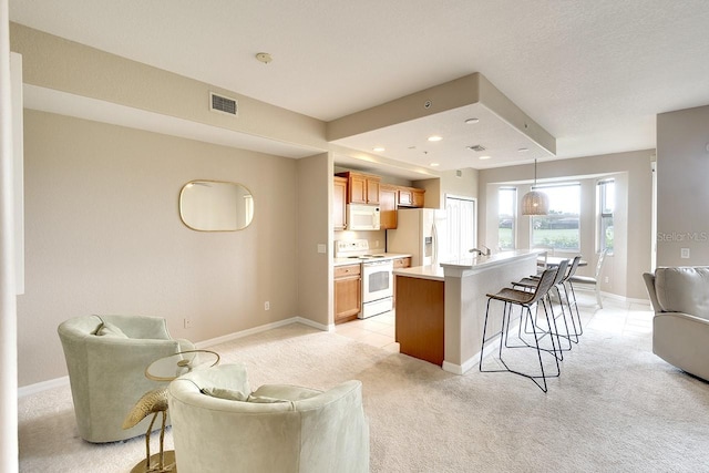 kitchen with pendant lighting, white appliances, a kitchen breakfast bar, a center island with sink, and light carpet