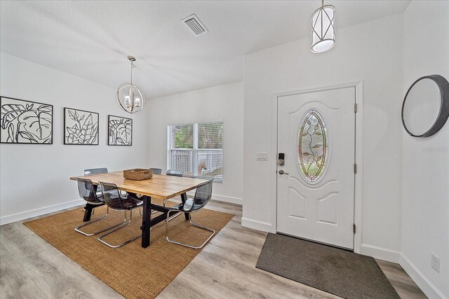 dining area with light hardwood / wood-style floors and a chandelier