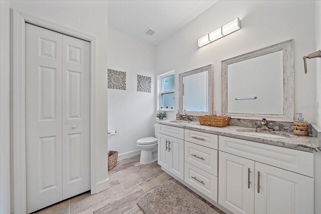 bathroom featuring tile patterned flooring, dual vanity, and toilet