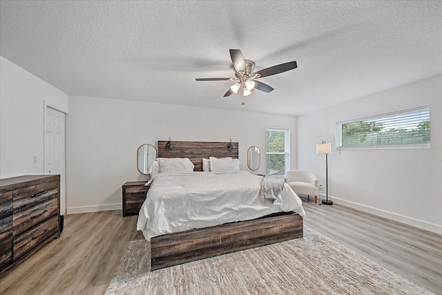 bedroom with a textured ceiling, ceiling fan, light hardwood / wood-style floors, and a closet