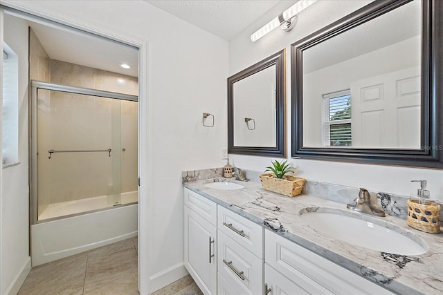 bathroom with dual vanity, combined bath / shower with glass door, tile patterned flooring, and a textured ceiling