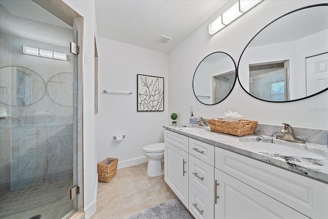 bathroom featuring double sink vanity, a shower with shower door, toilet, a textured ceiling, and tile patterned flooring