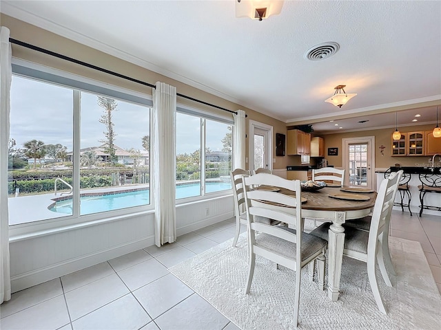 dining area featuring light tile patterned floors and crown molding