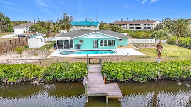 back of property featuring a sunroom, a yard, a shed, a water view, and a fenced in pool