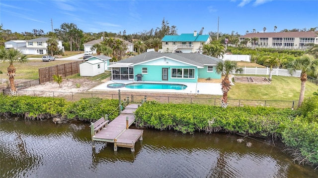 rear view of house featuring a lawn, a patio area, a storage shed, a fenced in pool, and a water view