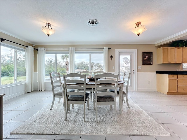 tiled dining area with a textured ceiling, a wealth of natural light, and ornamental molding