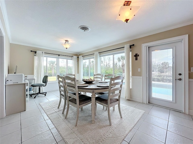 tiled dining room with a wealth of natural light, ornamental molding, and a textured ceiling