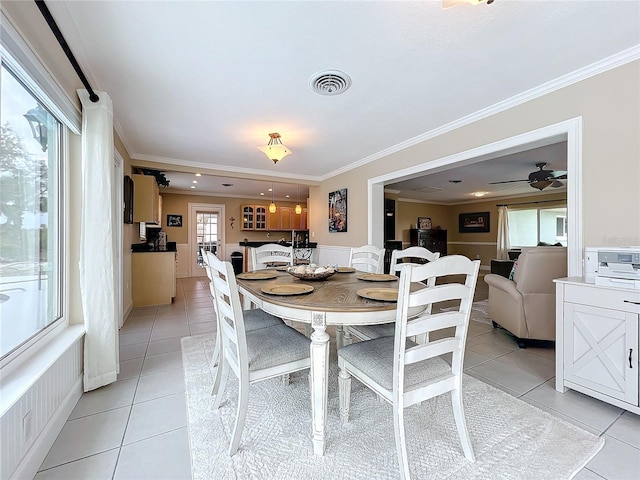 dining space featuring ceiling fan, light tile patterned flooring, and crown molding