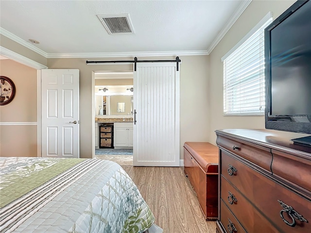 bedroom featuring a barn door, light hardwood / wood-style floors, crown molding, connected bathroom, and beverage cooler