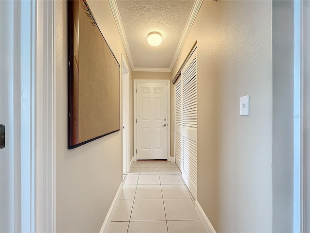 hallway featuring light tile patterned floors, ornamental molding, and a textured ceiling