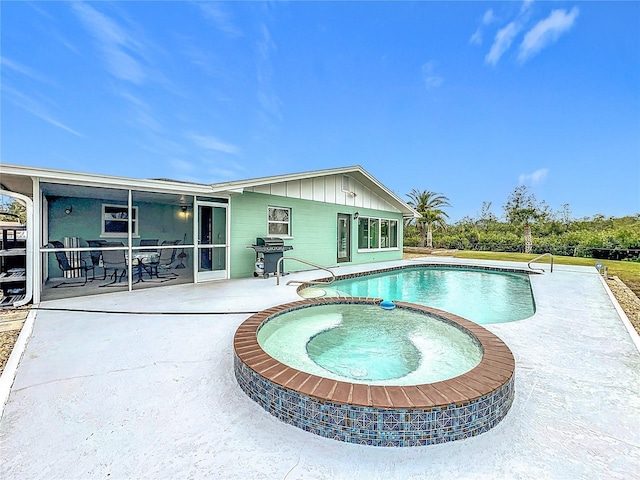 view of pool with a sunroom, area for grilling, a patio area, and an in ground hot tub