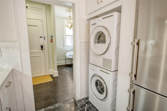 laundry room with dark hardwood / wood-style flooring and stacked washer / dryer