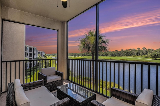 sunroom featuring ceiling fan and a water view