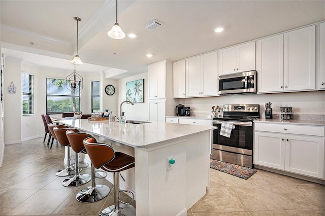 kitchen with stainless steel appliances, a kitchen island with sink, hanging light fixtures, white cabinets, and sink