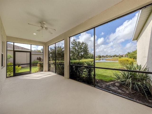 unfurnished sunroom featuring a ceiling fan and a water view