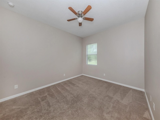 carpeted empty room featuring baseboards and a ceiling fan