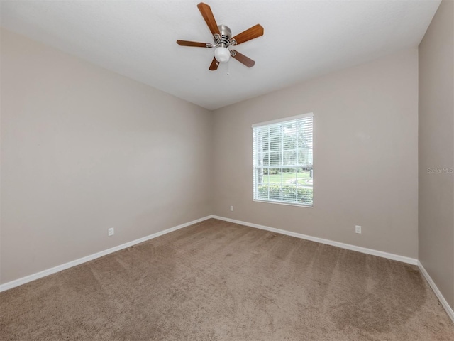 carpeted empty room featuring ceiling fan and baseboards