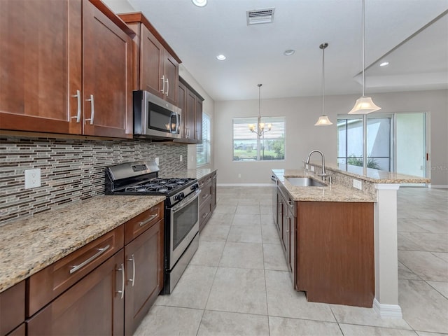 kitchen with visible vents, appliances with stainless steel finishes, light stone counters, hanging light fixtures, and a sink