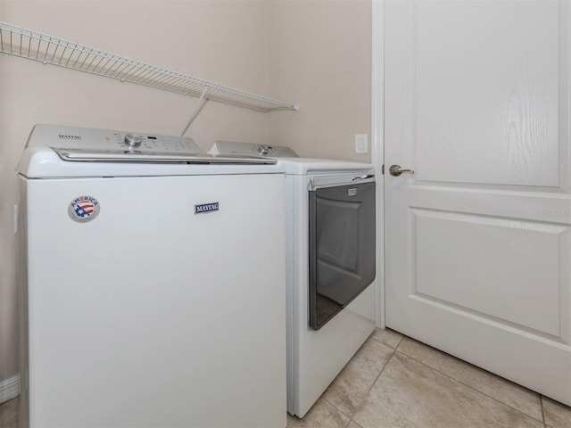 laundry room featuring laundry area, washing machine and dryer, and light tile patterned flooring