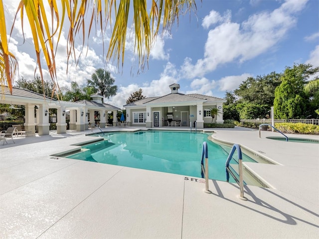 community pool featuring a hot tub, fence, and a patio