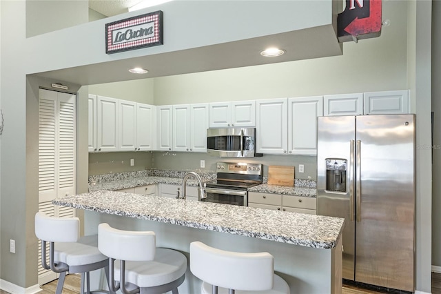 kitchen with appliances with stainless steel finishes, white cabinets, and light stone counters