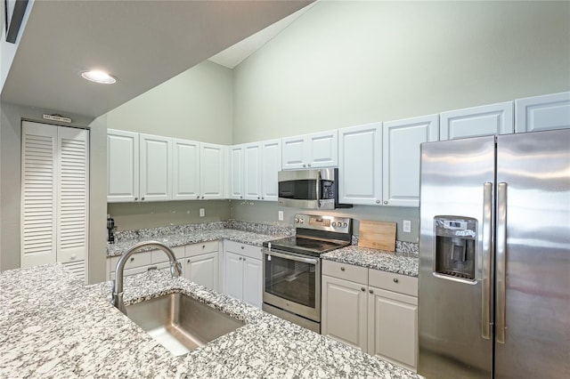 kitchen with sink, stainless steel appliances, white cabinets, and light stone countertops