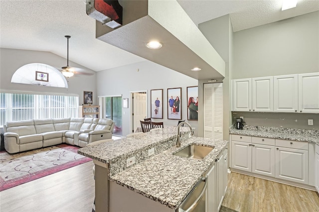 kitchen featuring sink, light hardwood / wood-style flooring, white cabinets, a center island with sink, and stainless steel dishwasher