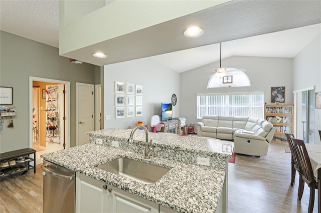 kitchen featuring an island with sink, sink, white cabinets, and light hardwood / wood-style flooring