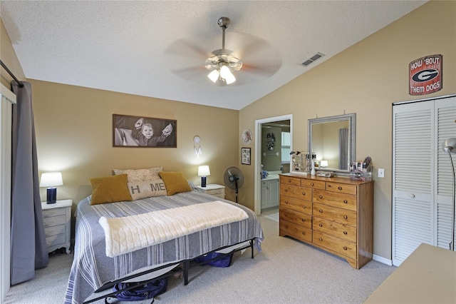 carpeted bedroom featuring vaulted ceiling, ceiling fan, a textured ceiling, ensuite bath, and a closet