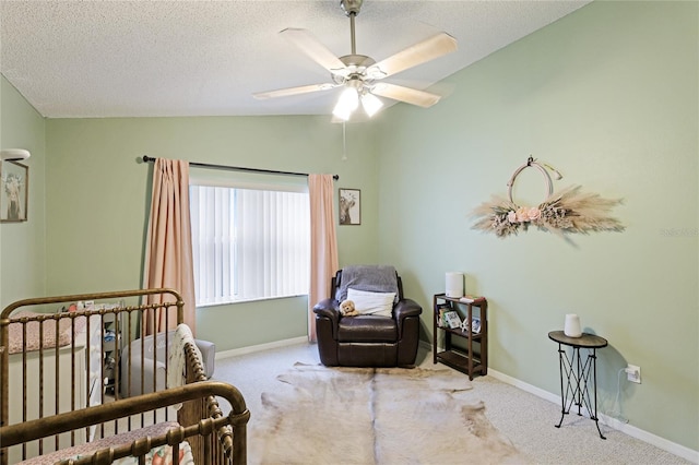 carpeted bedroom featuring ceiling fan, vaulted ceiling, a nursery area, and a textured ceiling