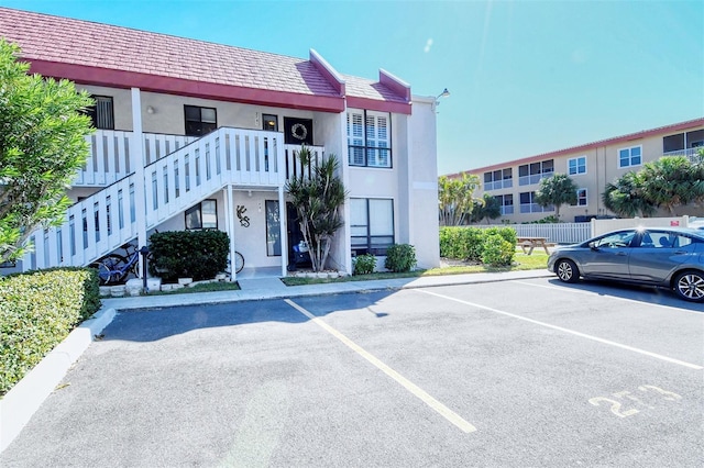 view of property featuring uncovered parking and stairs