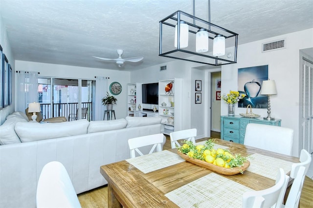 dining area featuring visible vents, a textured ceiling, and light wood finished floors