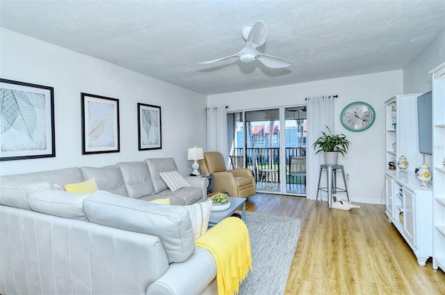 living area featuring light wood-type flooring, ceiling fan, a textured ceiling, and baseboards