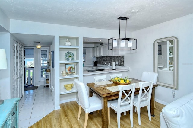 dining room featuring light wood-style floors, baseboards, arched walkways, and a textured ceiling