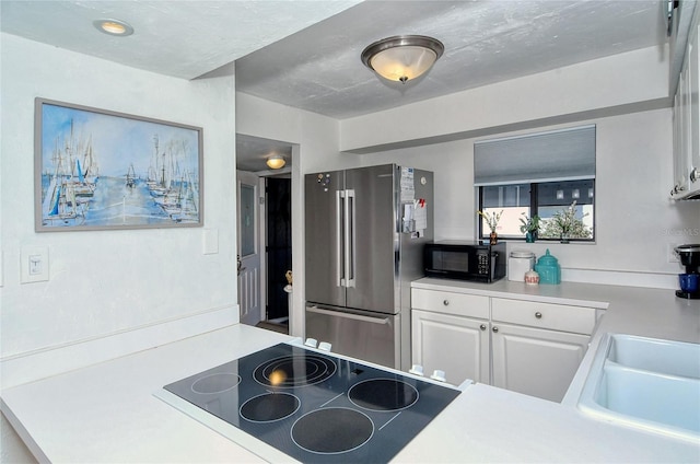 kitchen featuring a sink, black appliances, light countertops, and white cabinetry