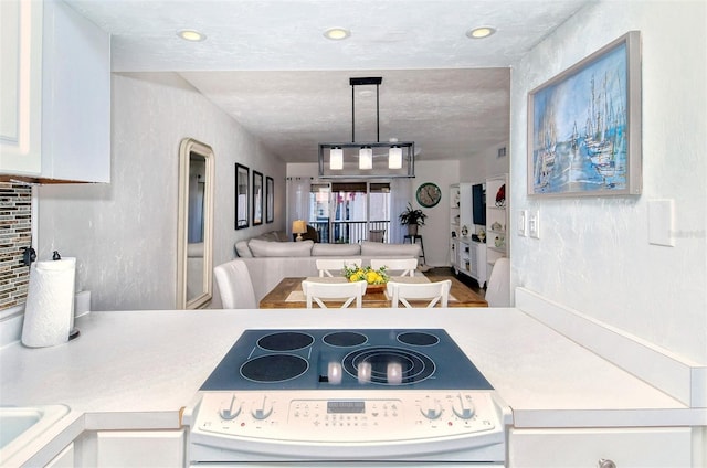 kitchen featuring electric range, white cabinets, light countertops, decorative backsplash, and pendant lighting