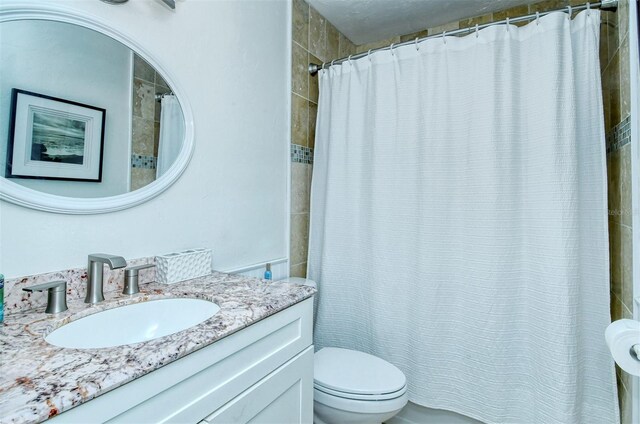 bathroom featuring curtained shower, vanity, and toilet