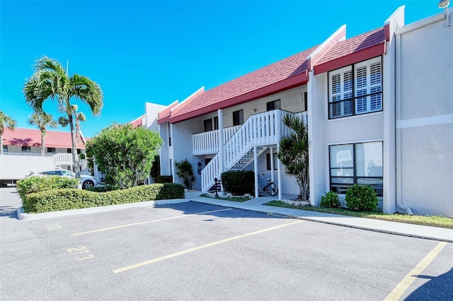 view of property with stairs and uncovered parking