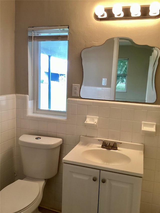 bathroom featuring vanity, toilet, and tile walls