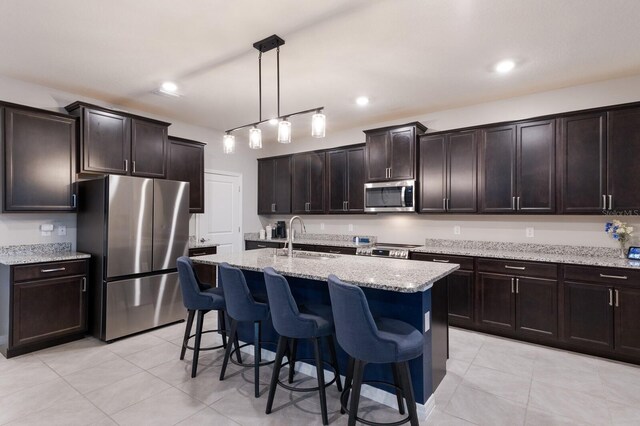 kitchen with light tile patterned flooring, stainless steel appliances, and dark brown cabinetry