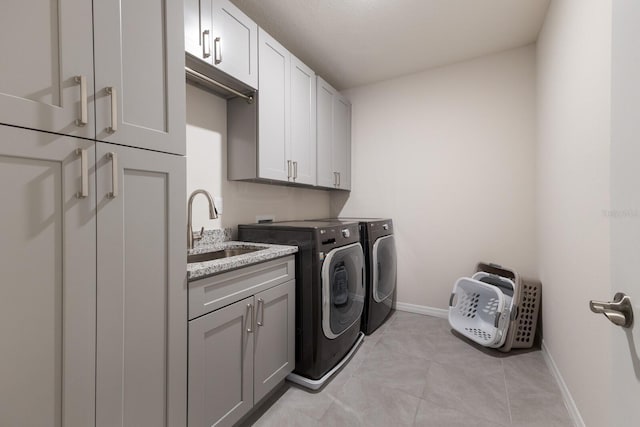 clothes washing area with sink, light tile patterned floors, washing machine and dryer, and cabinets